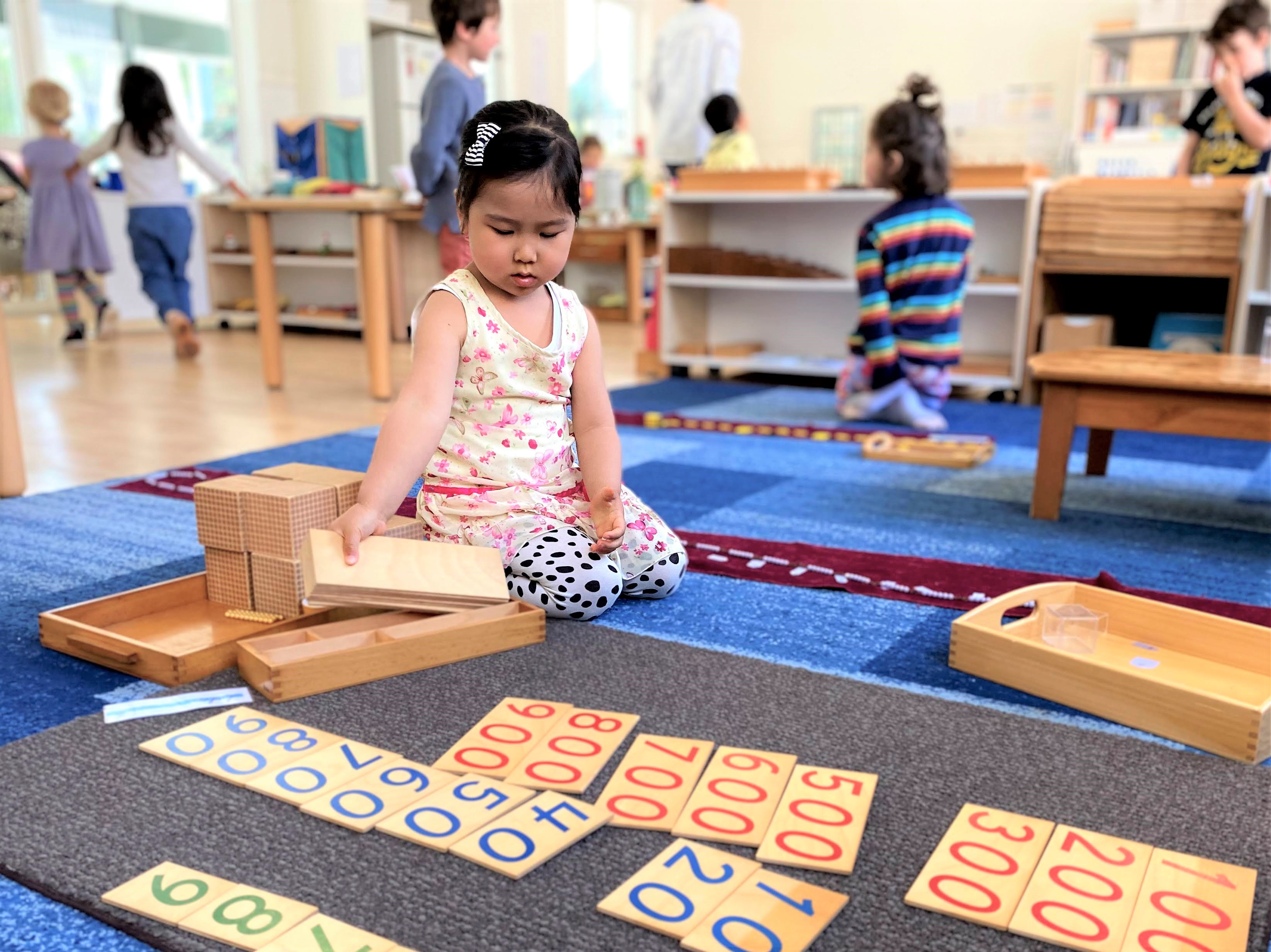 Cycle 1 3-6 Montessori Child using Number Cards to do maths at Montessori East Primary and Pre School